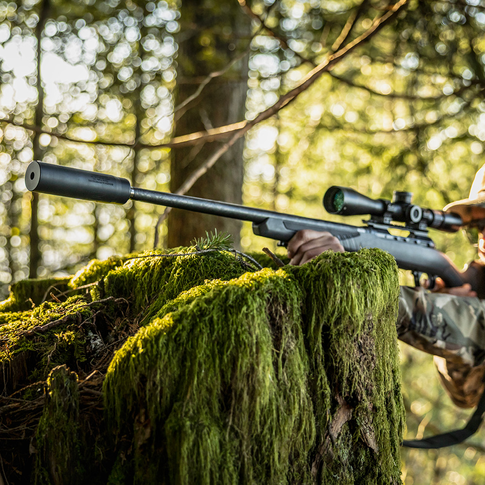 Man shooting a Banish HNT 30 suppressor on a bolt action rifle in the woods
